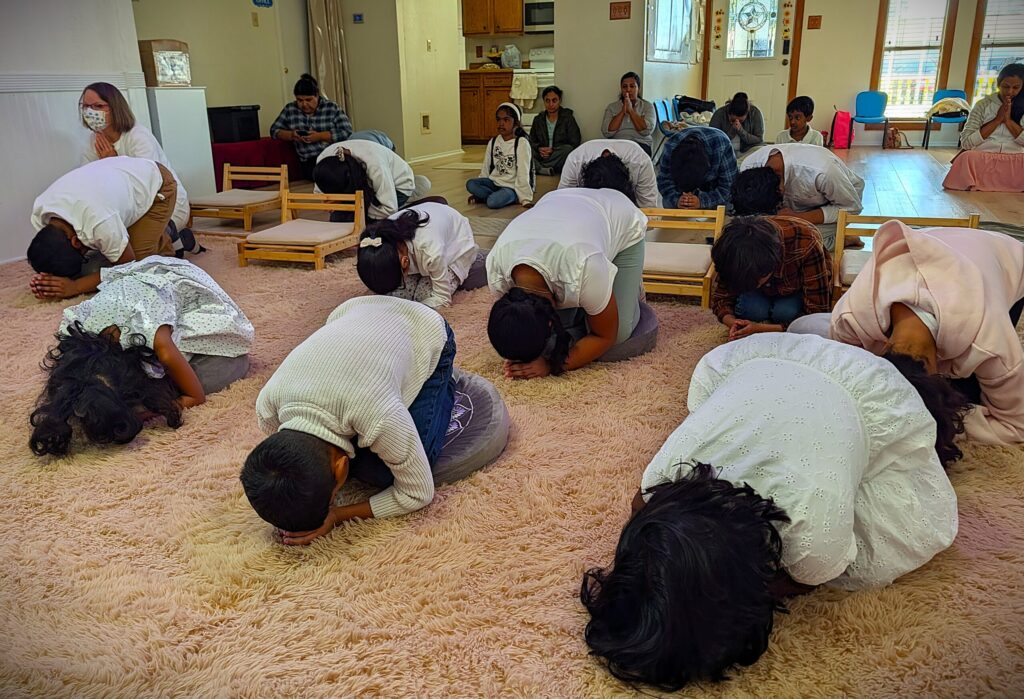 Dhamma School students bowing in deep worship of the Triple Gem—Buddha, Dhamma, and Sangha.